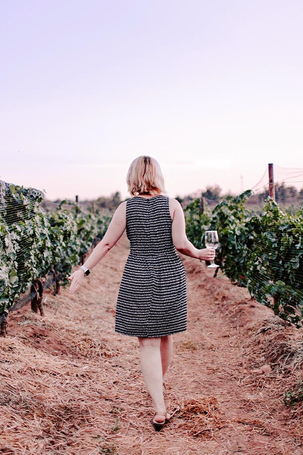 A woman holding a wine glass while walking through a vineyard in Mendoza, Argentina’s wine capital.