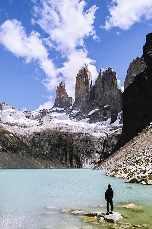 Boats in the water near a massive glacier in Patagonia, with snowcapped mountains overhead.