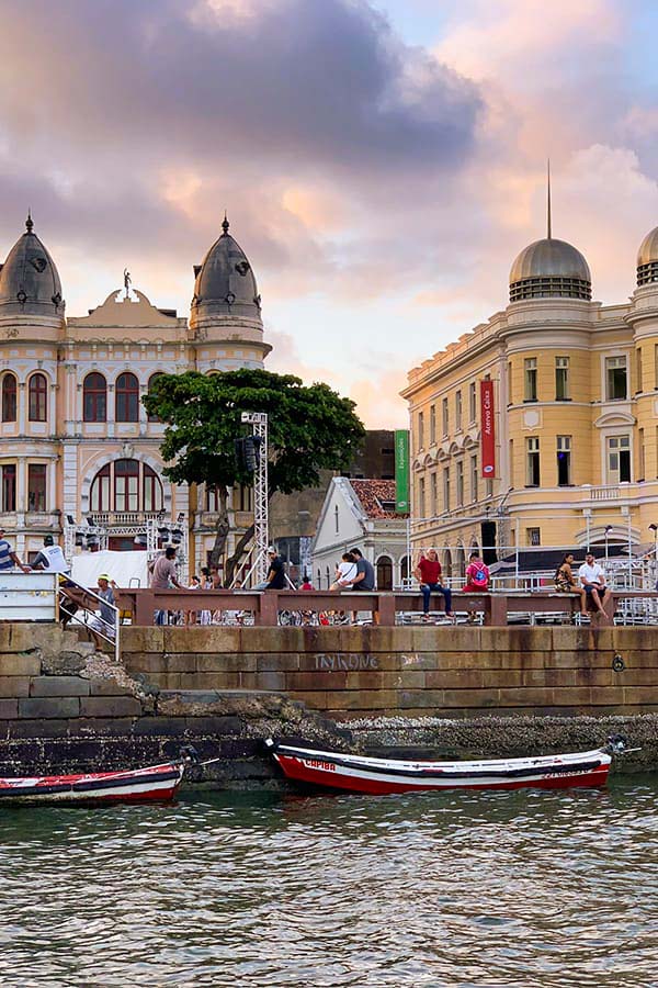 Colorful colonial buildings lining a modern road, as seen from the water in Recife.