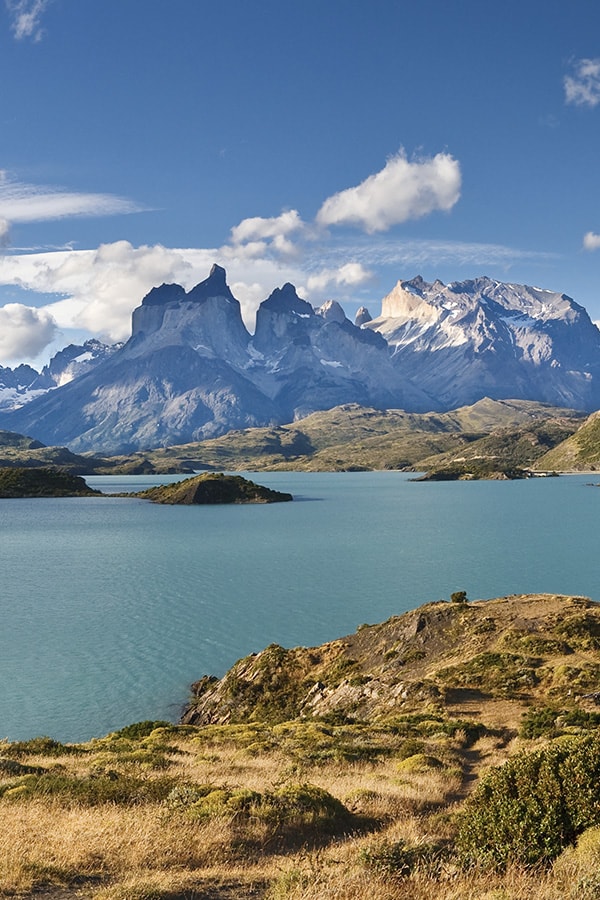 A blue lake overlooked by snow-capped peaks as well as the back of the iconic Torres del Paine.