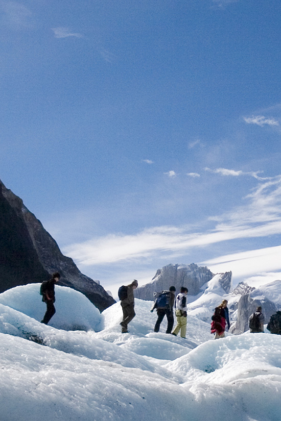 A group of trekkers hiking through snow-filled terrain in Torres del Paine National Park.