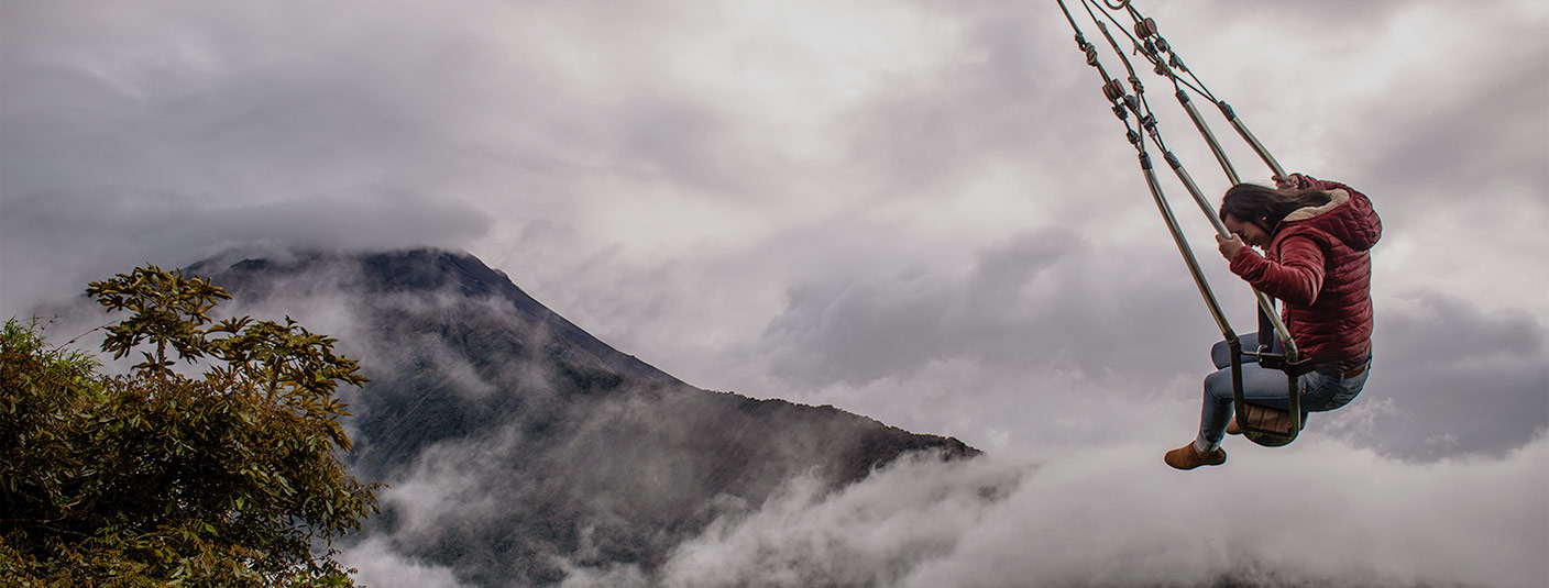 A woman swinging above the cloud forest on the Swing at the End of the World in Baños.