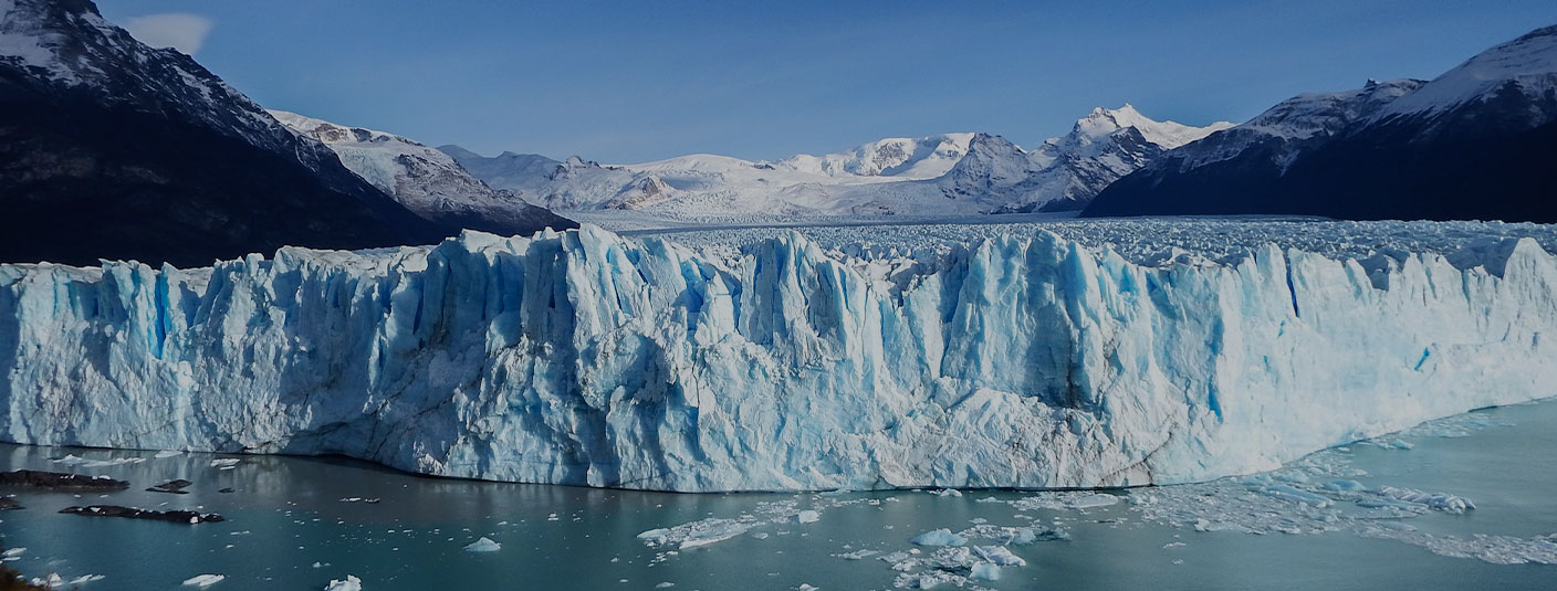 Panoramic view of the blue-tinted Perito Moreno glacier and surrounding mountains.