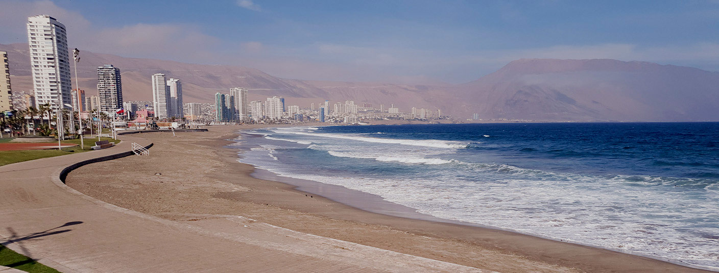 A beach and promenade lined by modern high-rise buildings in the Chilean city of Iquique.