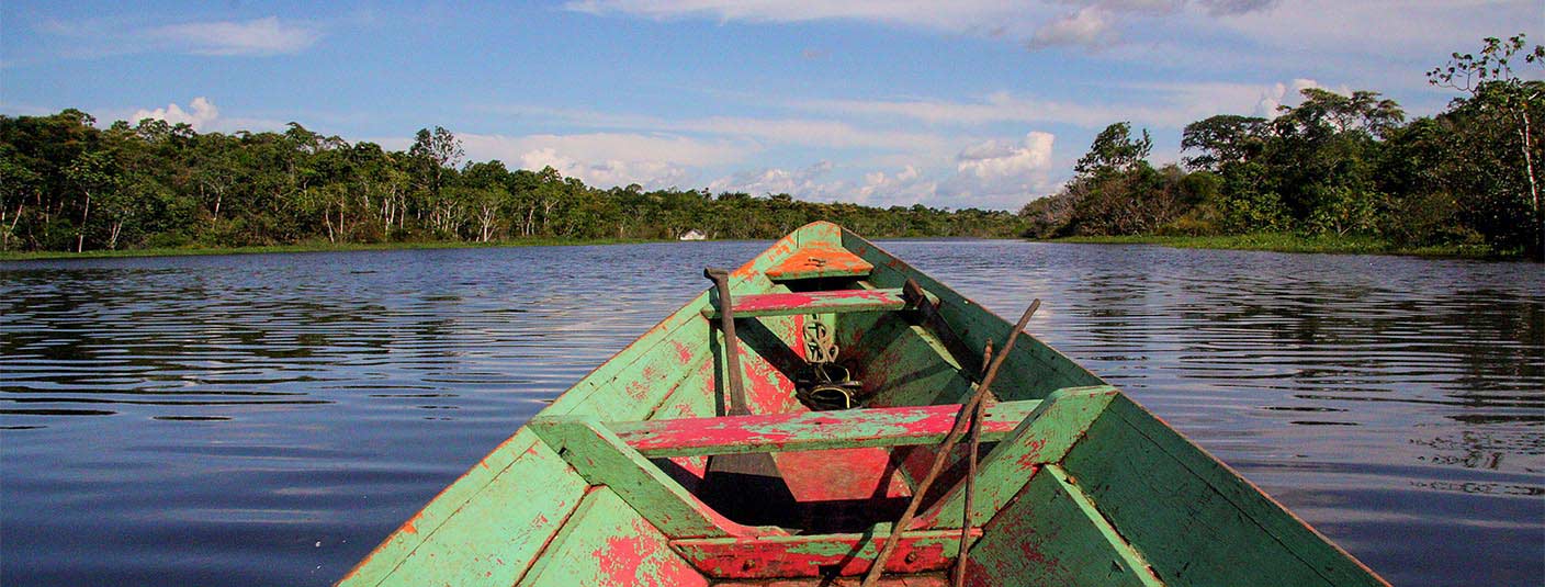 A small wooden boat floating on a river in the Amazon Rainforest near the city of Manaus.