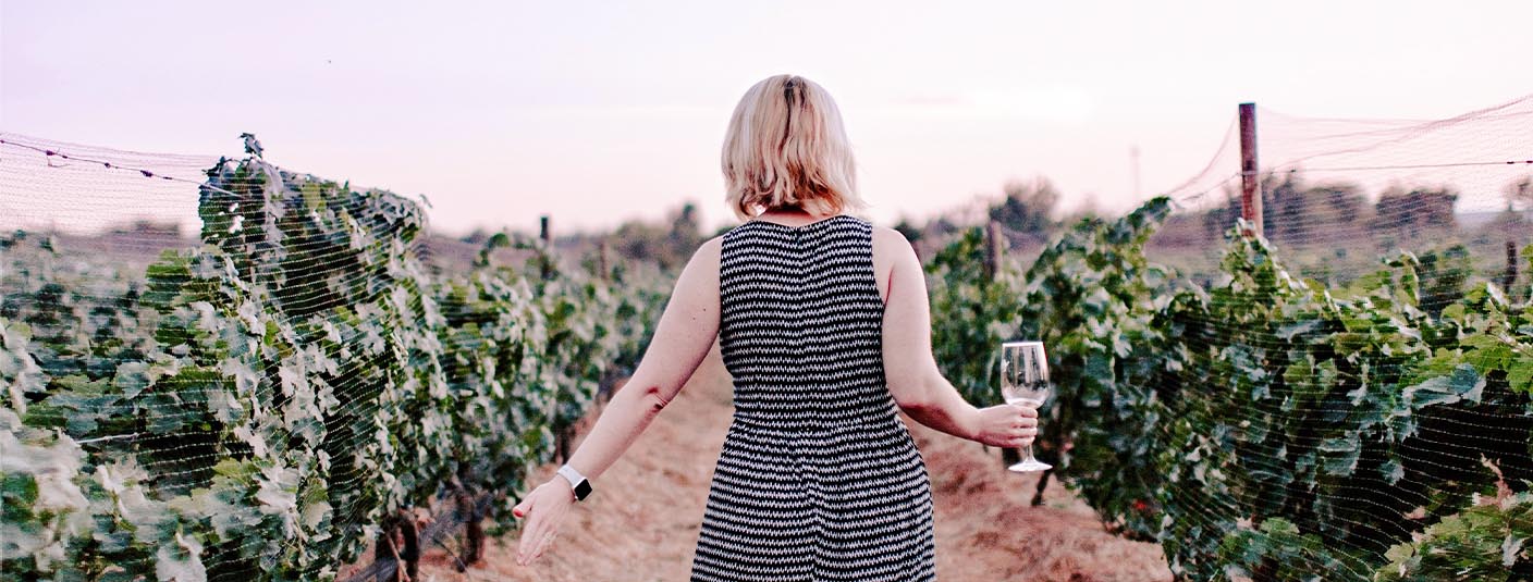 A woman holding a wine glass while walking through a vineyard in Mendoza, Argentina’s wine capital.