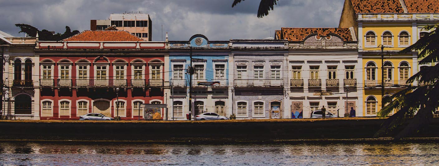 Colorful colonial buildings lining a modern road, as seen from the water in Recife.