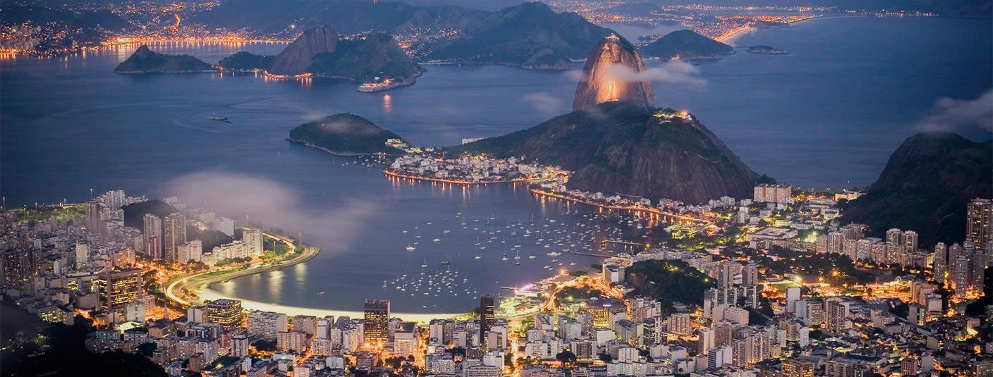 The city of Rio de Janeiro and the iconic Sugarloaf Mountain illuminated at night.