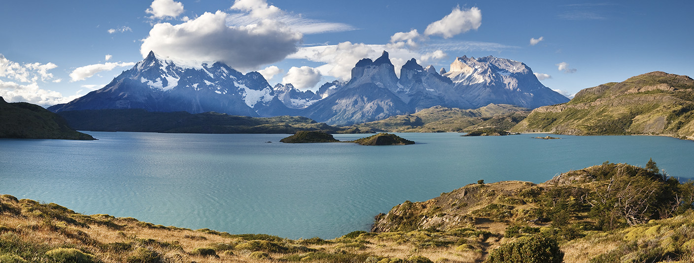 A blue lake overlooked by snow-capped peaks as well as the back of the iconic Torres del Paine.