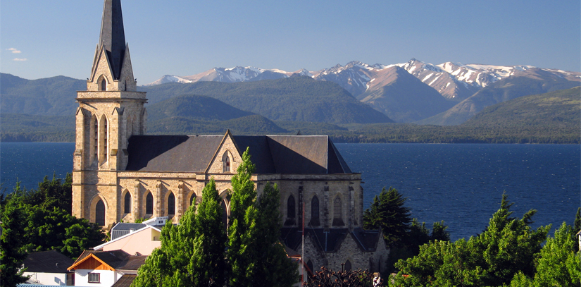 The Nuestra Señora del Nahuel Huapi Cathedral, with a lake and mountains as a backdrop