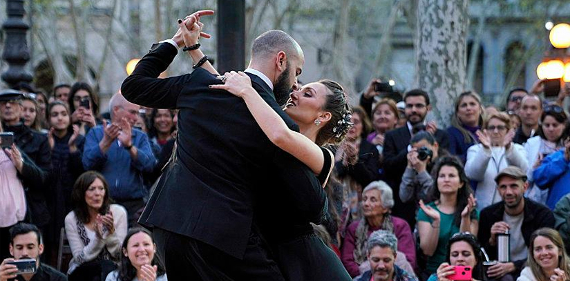 Two tango dancers dancing with spectators in the background