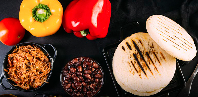 Arepas from the Galapagos, with bowls containing meat and beans and three peppers