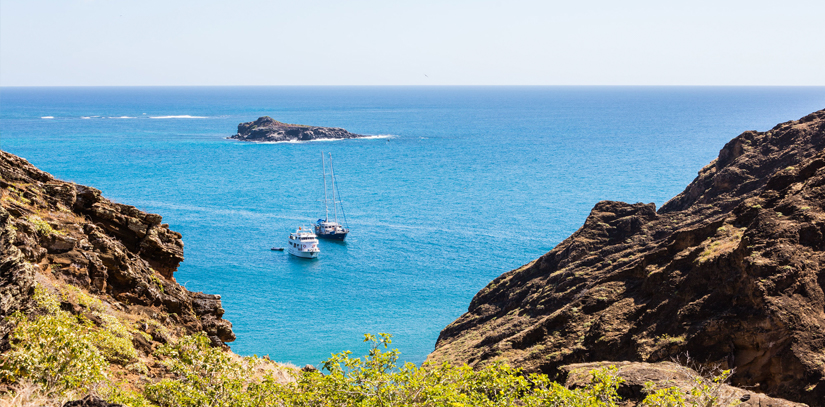 Two boats in the distance surrounded by blue ocean