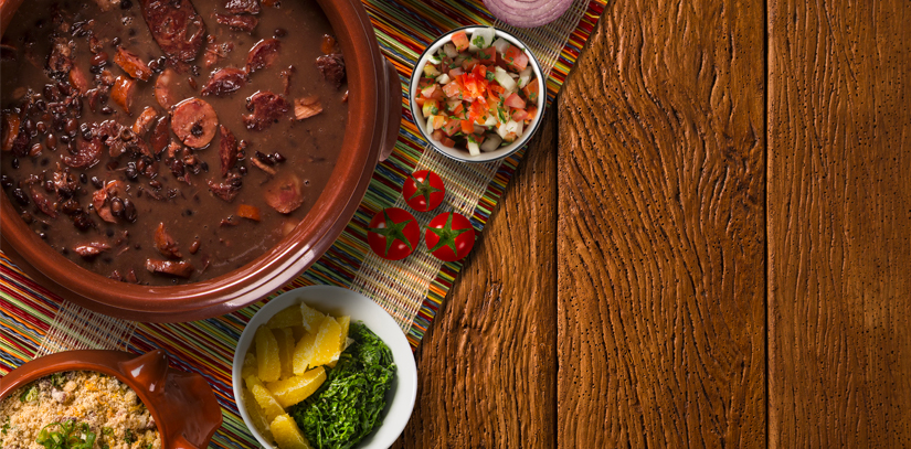 A bowl of feijoada stew, one of Brazil's most iconic dishes, with some small bowls of toppings