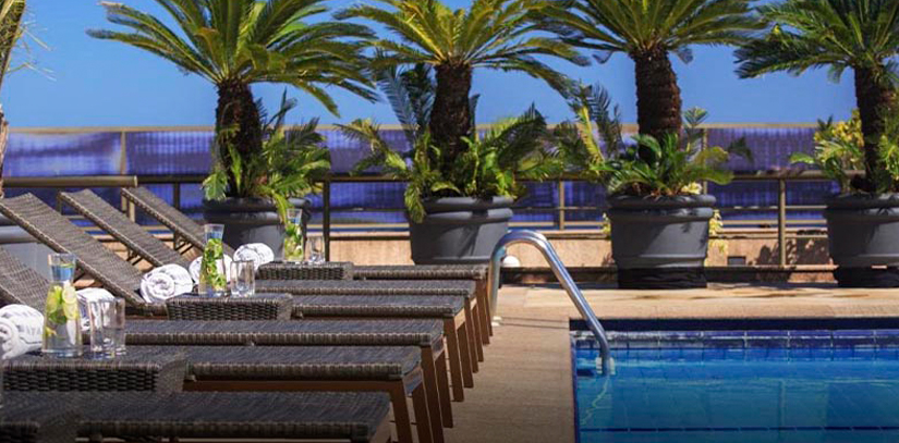 Sunbeds overlooking a blue pool surrounded by palm trees at the JW Marriot in Rio