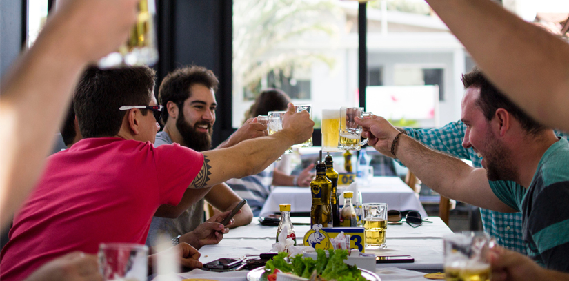 A group of men doing a toast with their beers in a restaurant in Rio