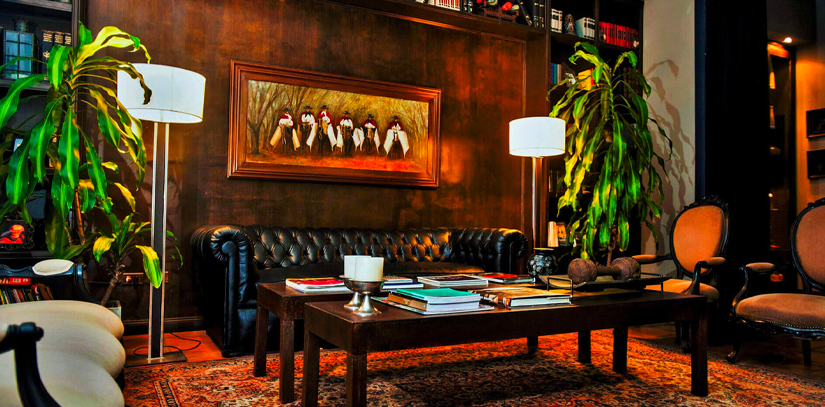 A colorful lobby of the 5-star Boutique Legado Mitico, a black leather couch is surrounded by beautiful large green plants