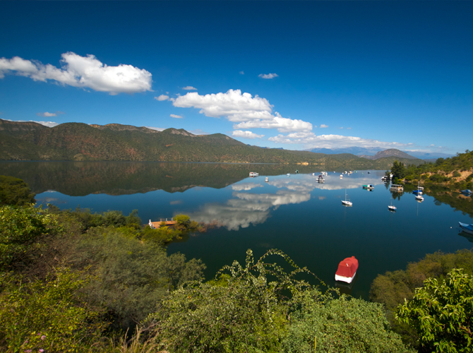 Cabra Corral lake stretching into the distance, with various boats floating above the water and mountains in the distance