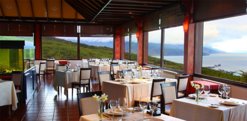 Tables and chairs in The Chez Manu restaurant overlooking the lake in Ushuaia.