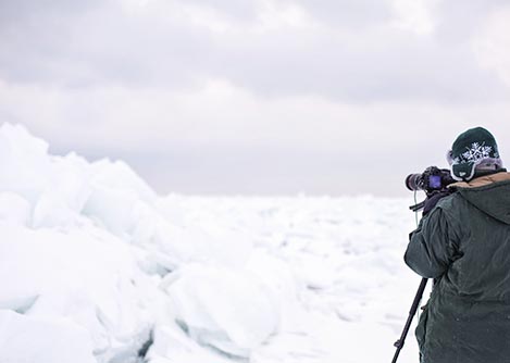 A visitor in Antarctica with a tripod set up, taking a photo of the icy landscapes.