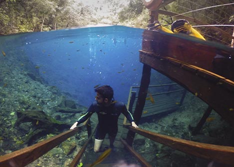 A man wearing diving gear walking up a staircase from the Lago Misteriosa in Bonito.