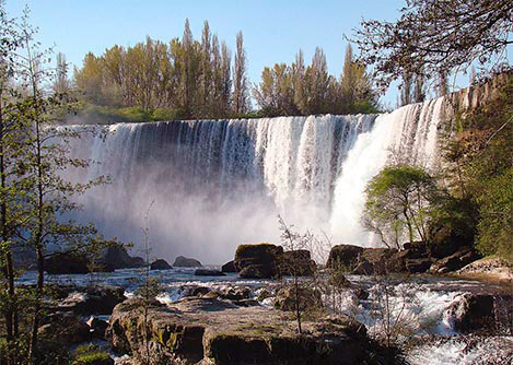The breathtaking Laja Falls near the city of Chillán, surrounded by forest scenery.