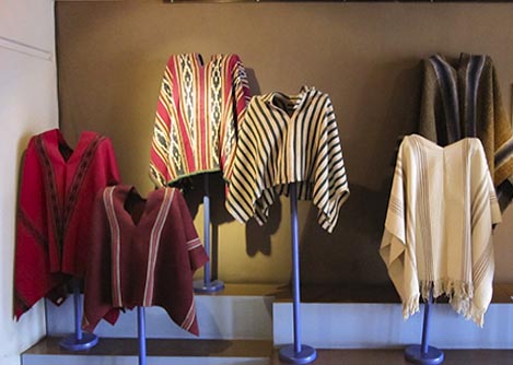 Ponchos with colorful traditional designs on display at the Museo del Banco Central in Cuenca.