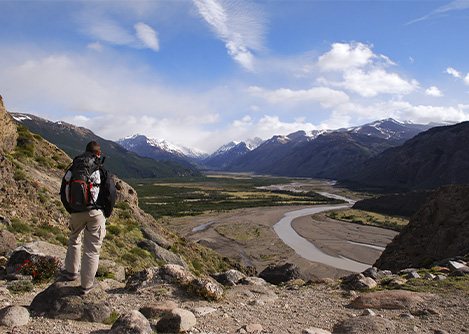 A hiker stopped on a trail and looking out at a valley surrounded by mountains near El Chalten.