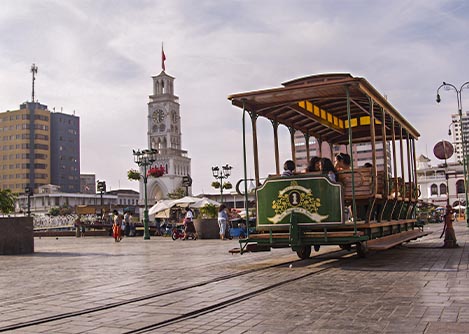 Visitors observing the main square of Iquique from a historic street car on a track.