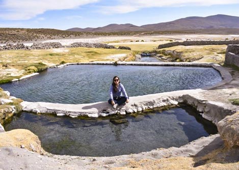 A woman sitting on a ledge between two pools at the Mamiña thermal springs near Iquique.