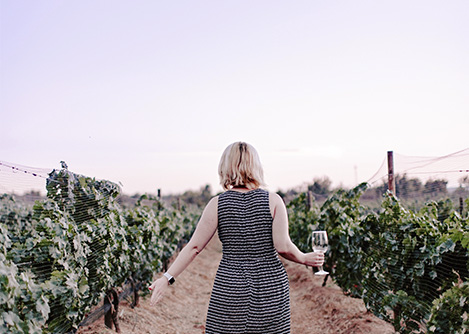 A woman holding a wine glass while walking through a vineyard in Mendoza, Argentina’s wine capital.