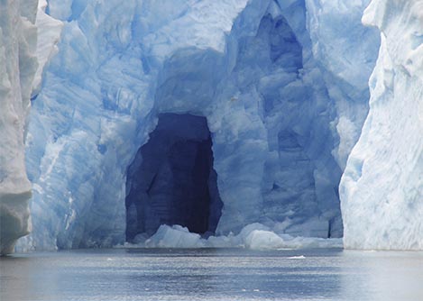 An ice cave inside the blue-tinted Grey Glacier, overlooking the adjacent Grey Lake.