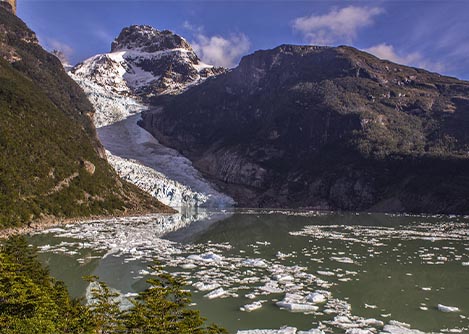 A green lake overlooked by the Serrano Glacier which empties into the lake from a nearby mountain.