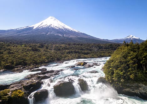 The Petrohue Waterfalls, surrounded by lush greenery and overlooked by the Osorno Volcano.