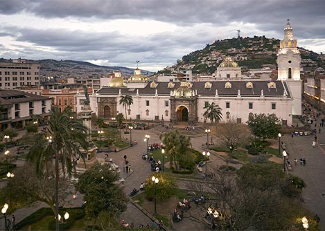 The main square of Quito in early evening, with the famous Panecillo Hill visible in the distance.