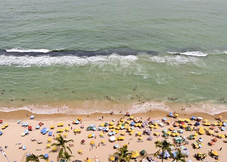 An aerial view of Boa Viagem beach in Recife, with many beach umbrellas dotting the sand.