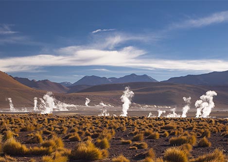 Vapor rising up from the geysers at El Tatio, surrounded by gorgeous mountain landscapes.