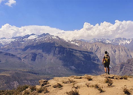A hiker with a backpack looking out at beautiful mountain landscapes in the Maipo Valley.